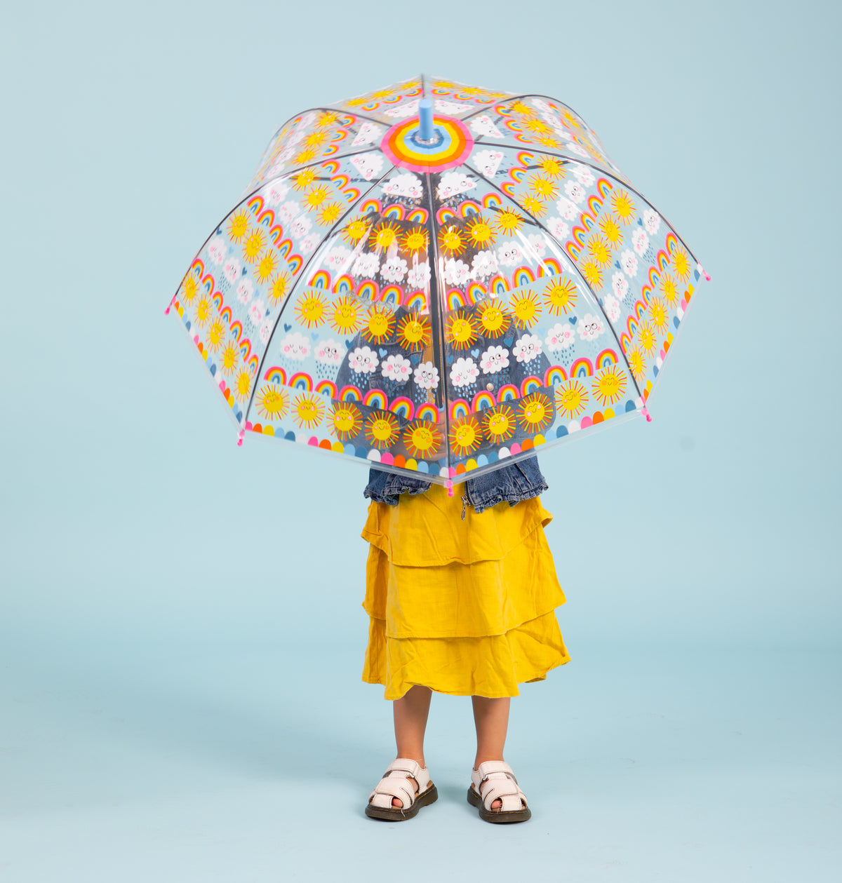 Child holding sun rainbows and clouds umbrella showing see-through dome with colorful rainbow and sun graphics"