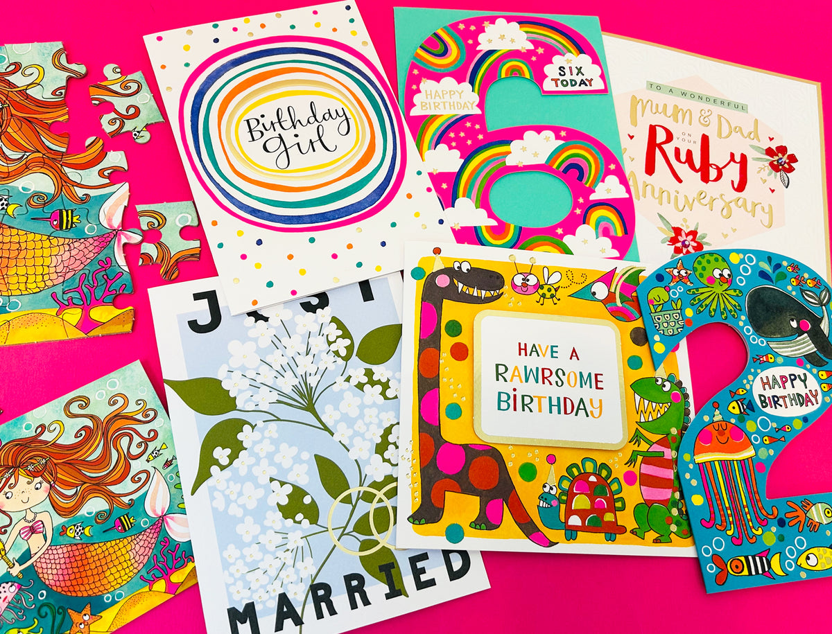Rachel Ellen Designs selection of greeting cards for birthdays, anniversaries, and weddings, featuring mermaid puzzle pieces and dinosaur designs.