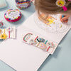 Children's desk with coloring book, markers, and decorative items on a light blue surface.