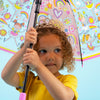 Girl holding fairy ballerina umbrella displaying clear dome with pink ballerinas and rainbow design