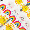Close-up detail of sun rainbows and clouds umbrella showing smiling yellow suns and rainbow stripes